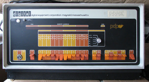 A DEC PDP-8F unit with a cream case prividing a striking contrast to a black front pannel with orange and yellow details