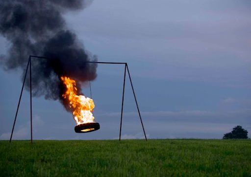 A tire swing blazes amidst an otherwise peaceful evening field